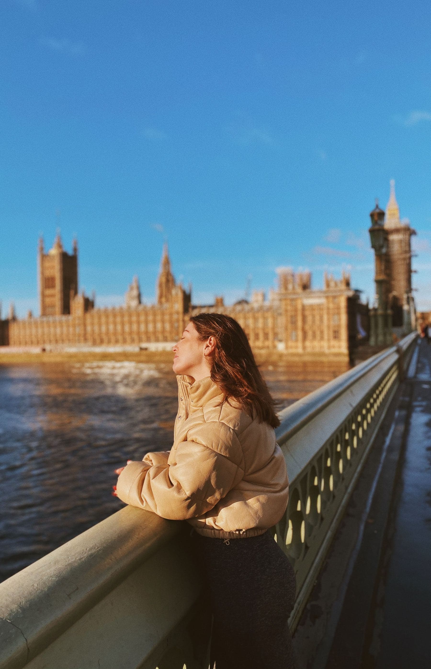 A young woman looking out from Westminster Bridge towards the Houses of Parliament.