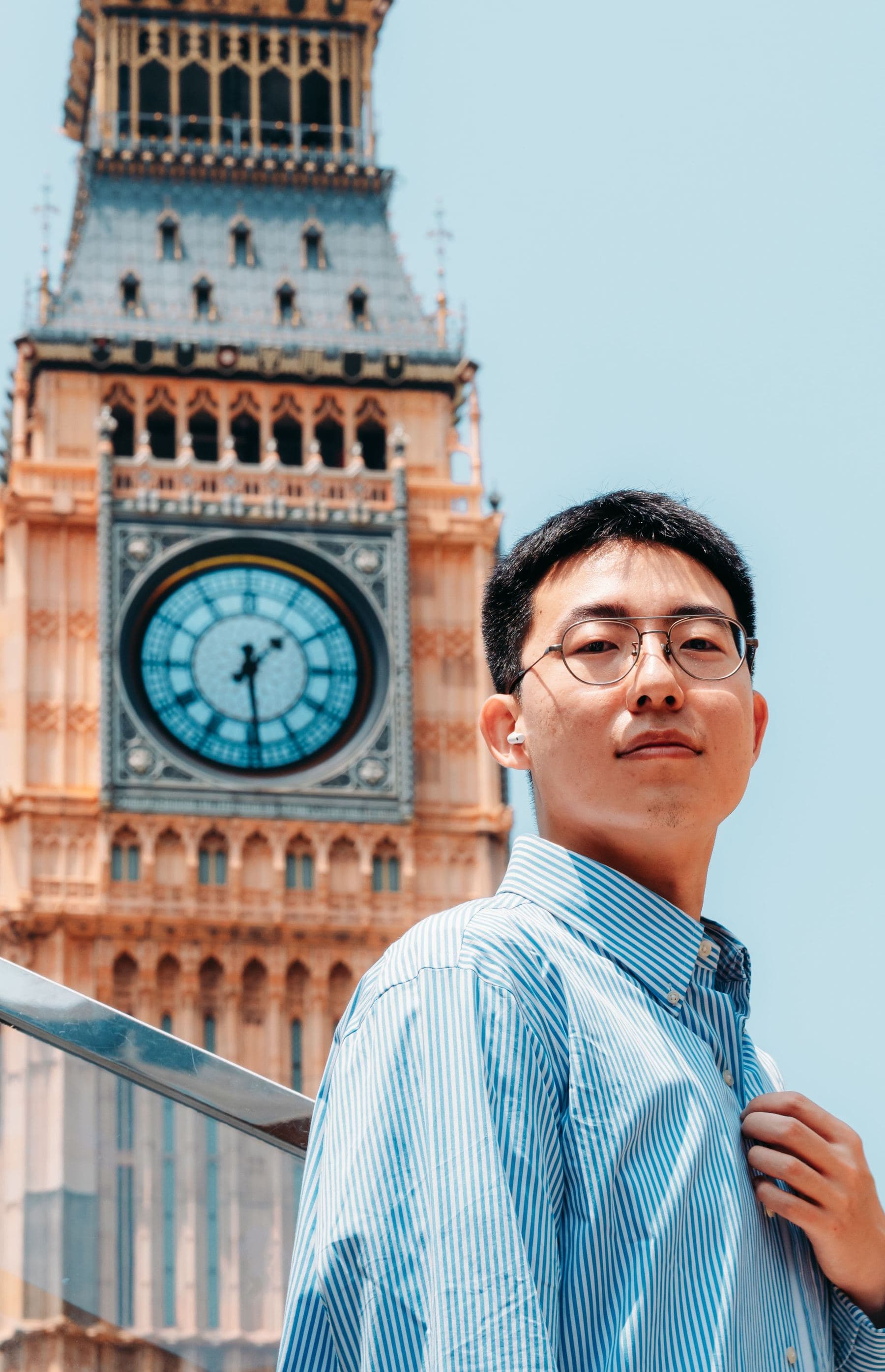 An international student outside the Elizabeth Tower, the Big Ben clock face behind him.